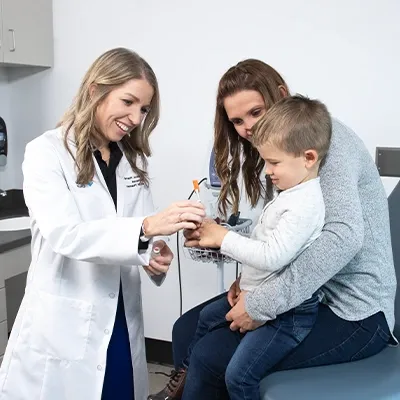 Nurse smiling and talking with a mother and son in doctor's office room