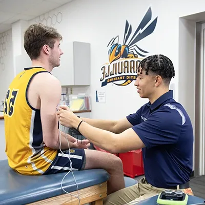Athletic training graduate student treating basketball player
